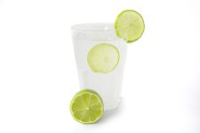 Fresh lemon juice in a clear glass decorated with slice of lemon  side view isolated on white background